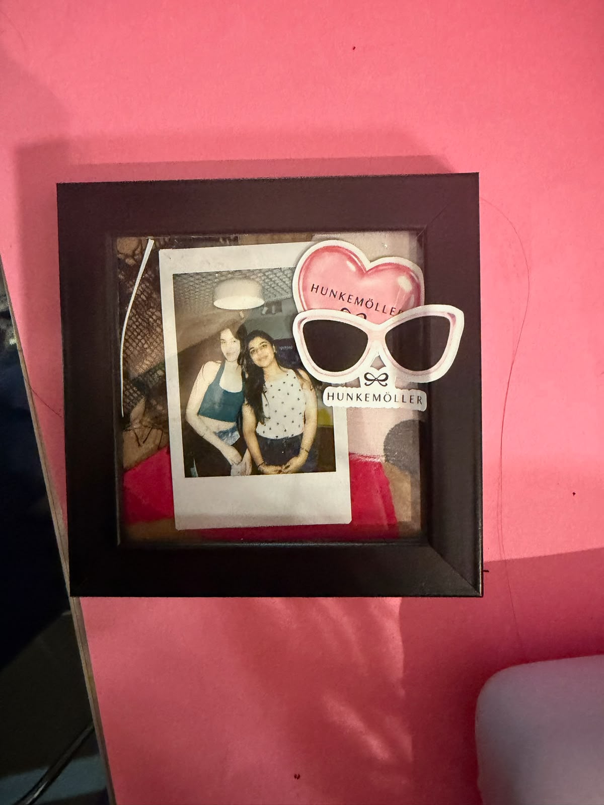 A guest Polaroid mounted in a black frame with Hunkemöller heart and sunglasses stickers.